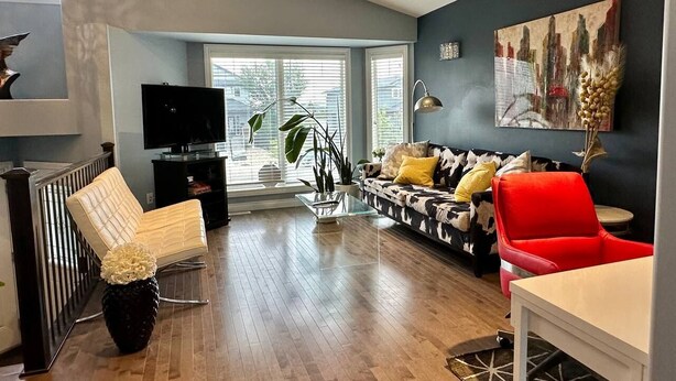 Un salon moderne avec un canapé, un fauteuil rouge et un téléviseur.