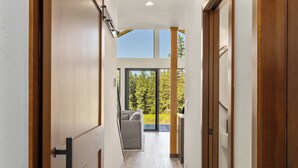Een modern interieur met een houten vloer, een bank en uitzicht op groen.