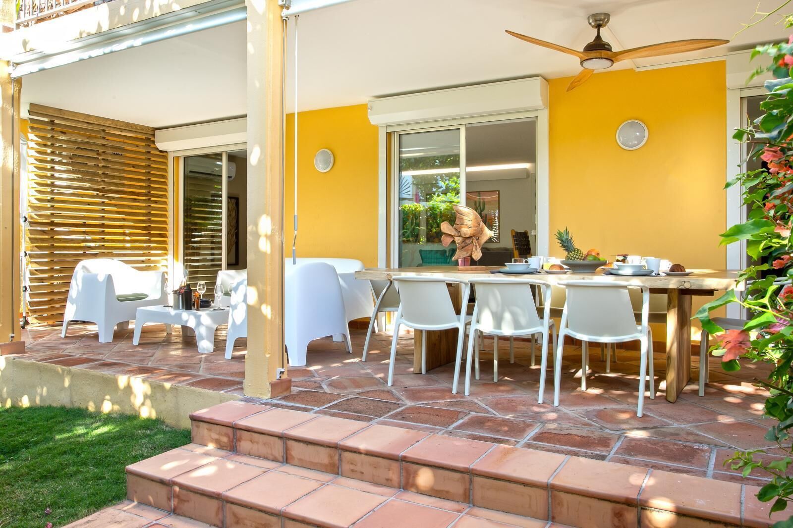 An outdoor patio with a dining table, chairs, and a ceiling fan.