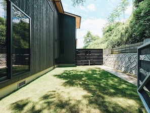 A modern house with a wooden exterior, a fenced backyard, and a clear sky.