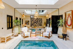 A modern interior with a pool, seating area, and potted plants.