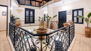 Varanda ampla com guarda-corpo de vidro, plantas em vasos e vista para o interior.