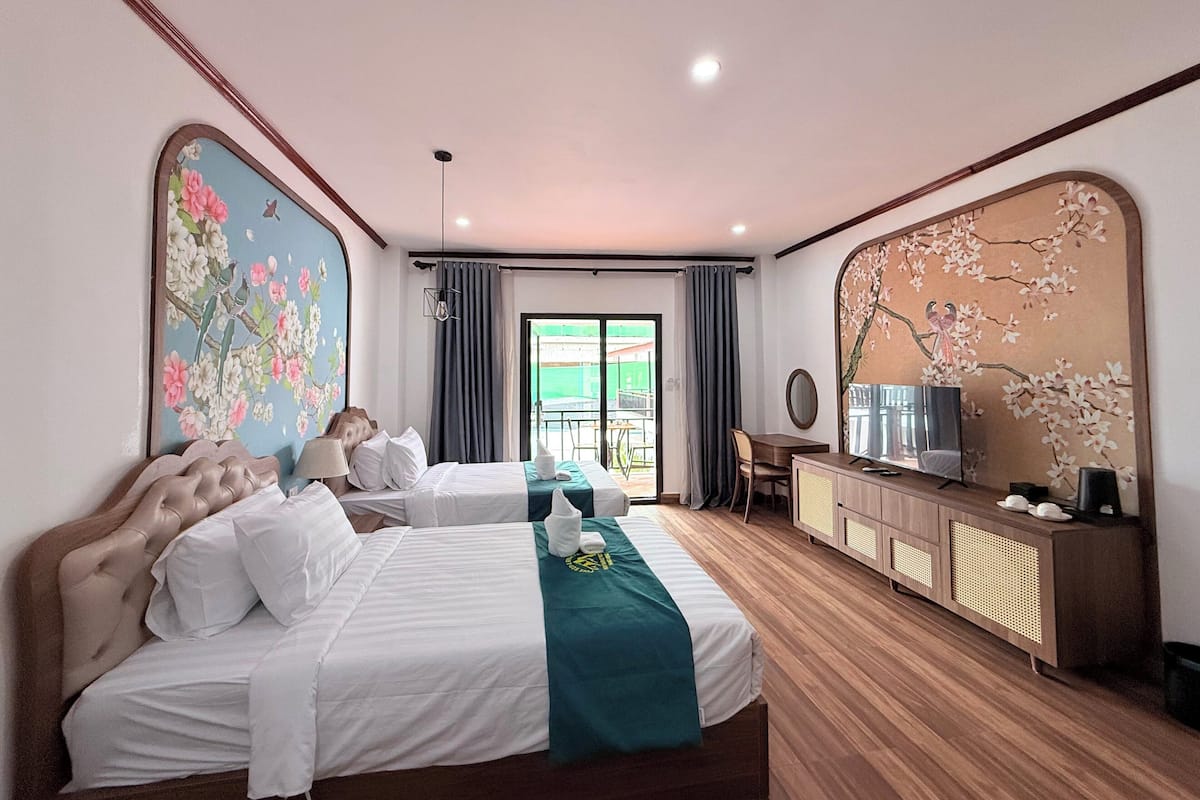 A hotel room with a bed, a desk, a television, and a large window.