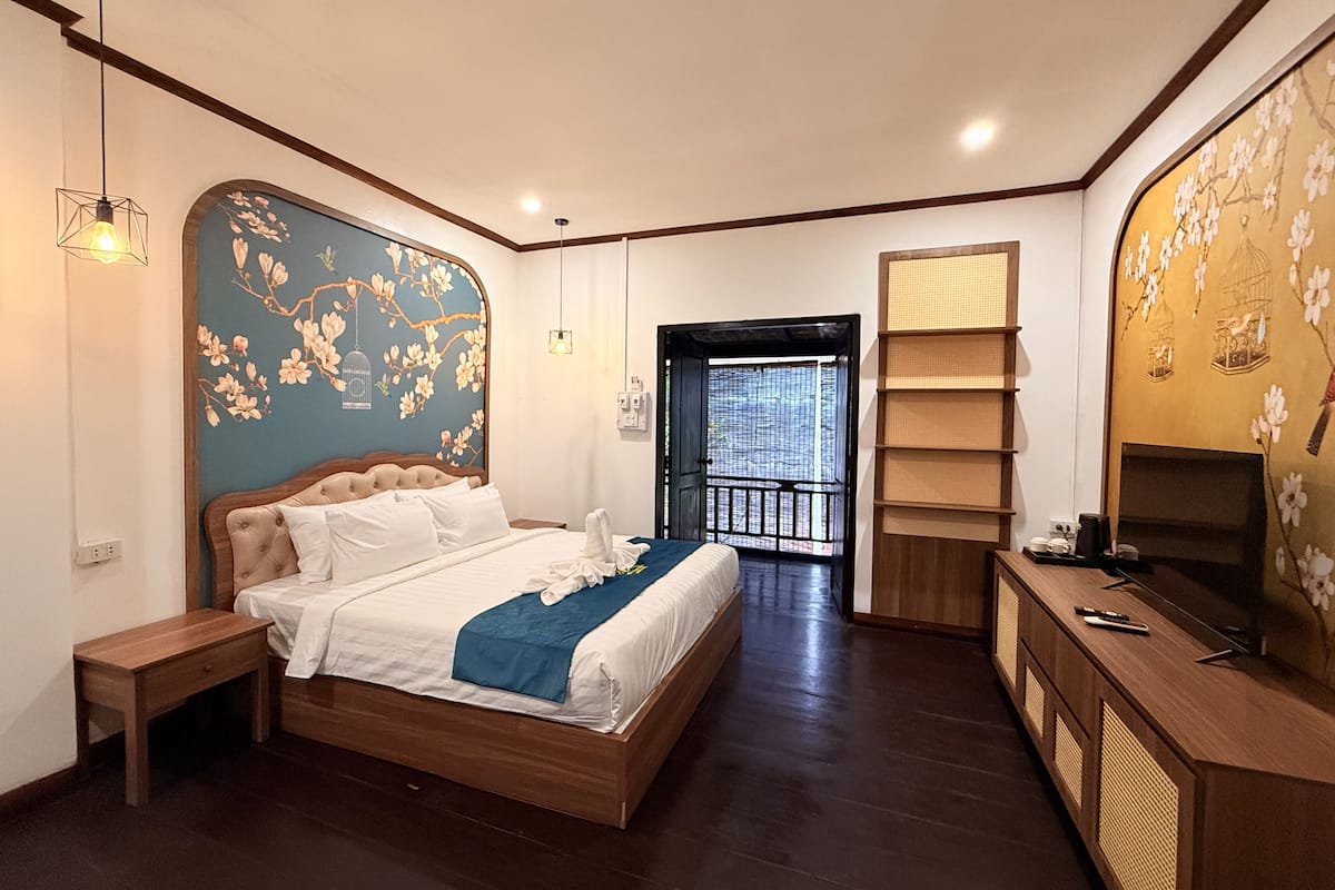 A bedroom with a bed, bedside table, and a TV stand with a TV.