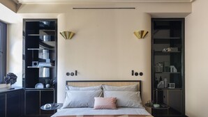 A bedroom with a bed, bedside tables, a wardrobe, and a built-in shelf unit with various items. - Homy® - The Signature Suite 2 (Milan)