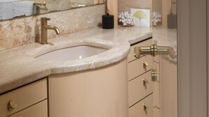 A bathroom with a large mirror, a sink, and a vanity with drawers.