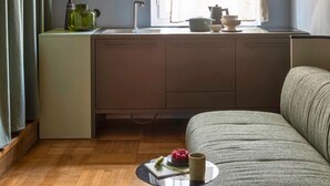 A compact living space with a kitchenette, a sofa, and a small table.