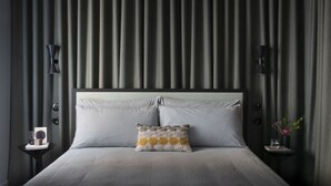 A modern bedroom with a large bed, two bedside tables, and a headboard with vertical lines.