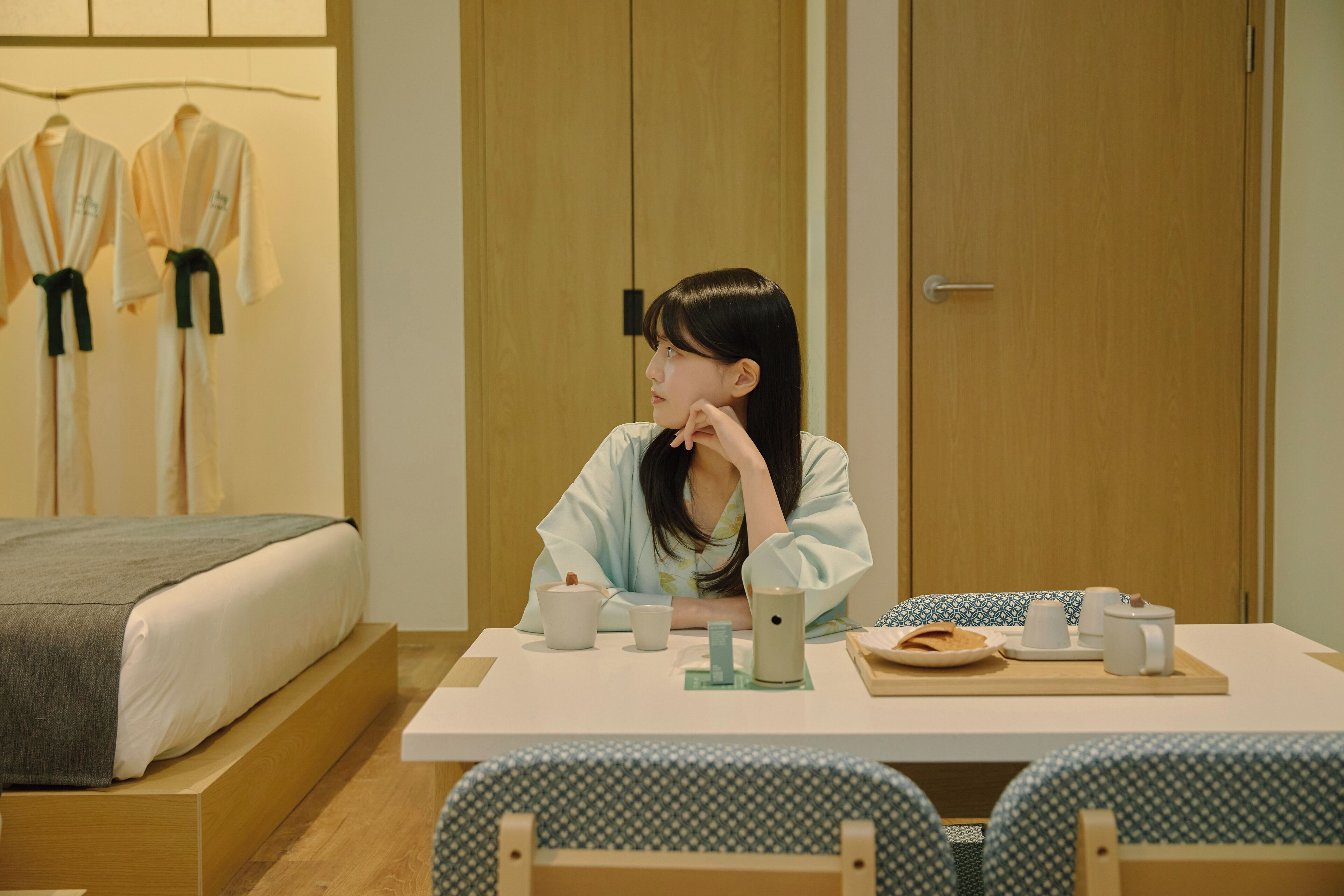 A room with a bed, a table with a tray of breakfast items, and a chair.