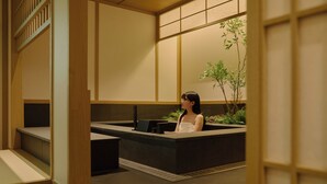 Un interior japonés tradicional con suelo de tatami, un escritorio de madera bajo y una planta en maceta.