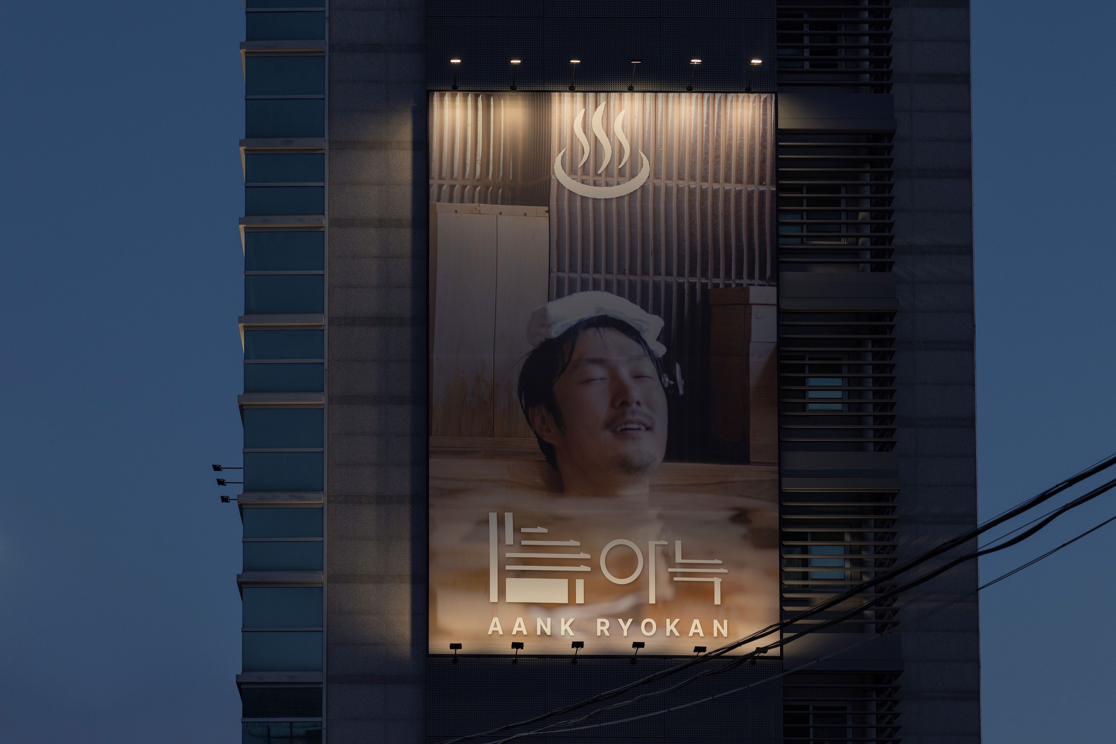 Un edificio con un gran cartel publicitario que anuncia 'AANK RYOKAN'.