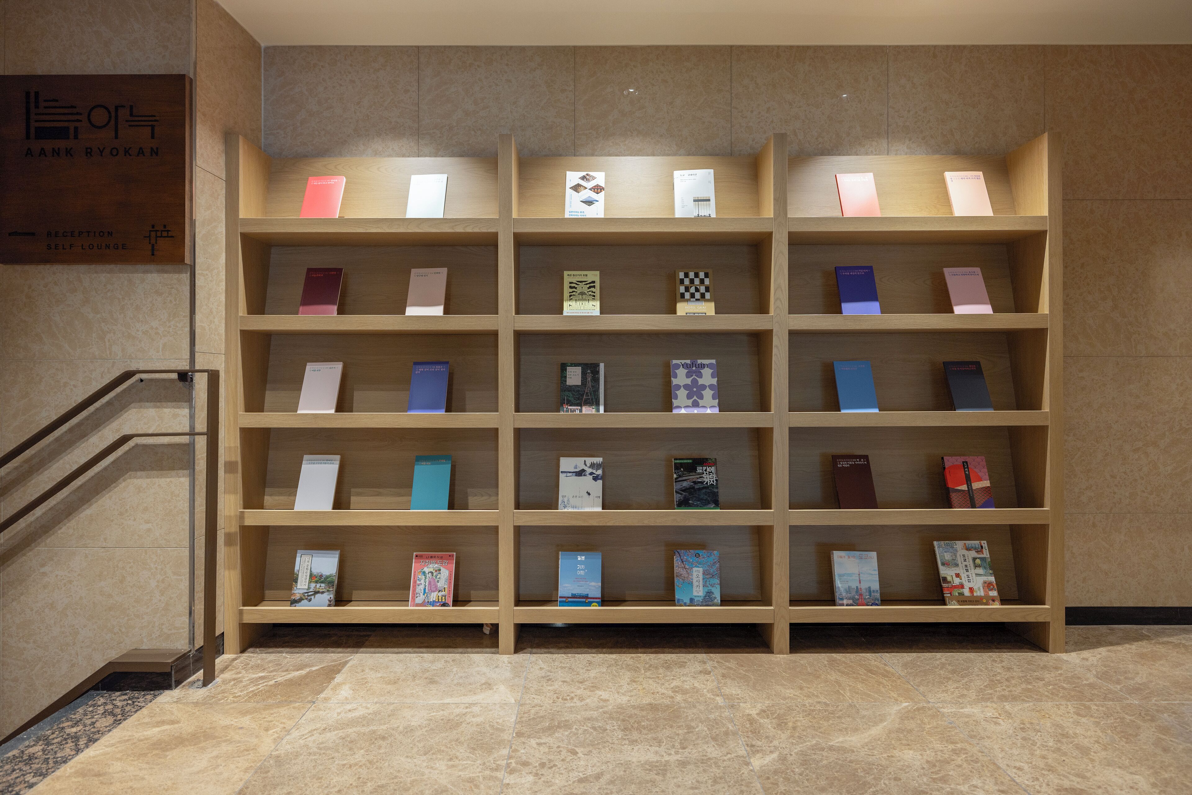 A reception area with a wooden bookshelf displaying various books and a sign indicating a self-lounge.