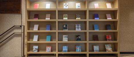 A reception area with a wooden bookshelf displaying various books and a sign indicating a self-lounge.