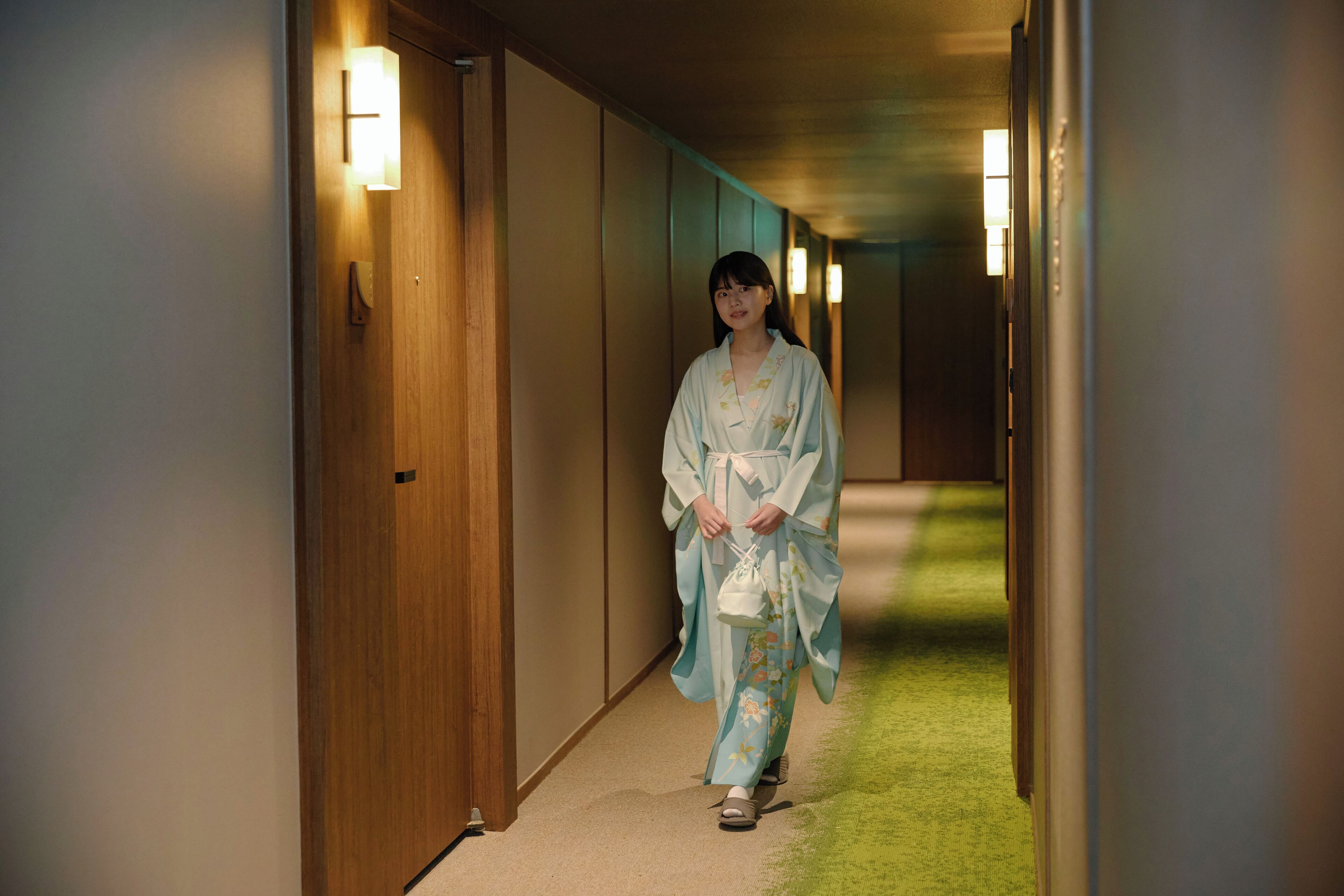 A hallway with wooden doors and wall-mounted lights.