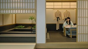 Un interior japonés tradicional con suelo de tatami, una mesa baja con cojín y un perchero colgante.