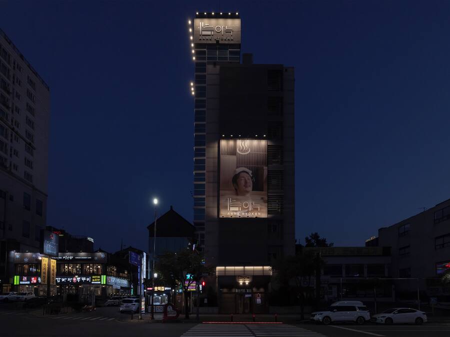 A hotel with a prominent sign, multiple floors, and a large billboard.
