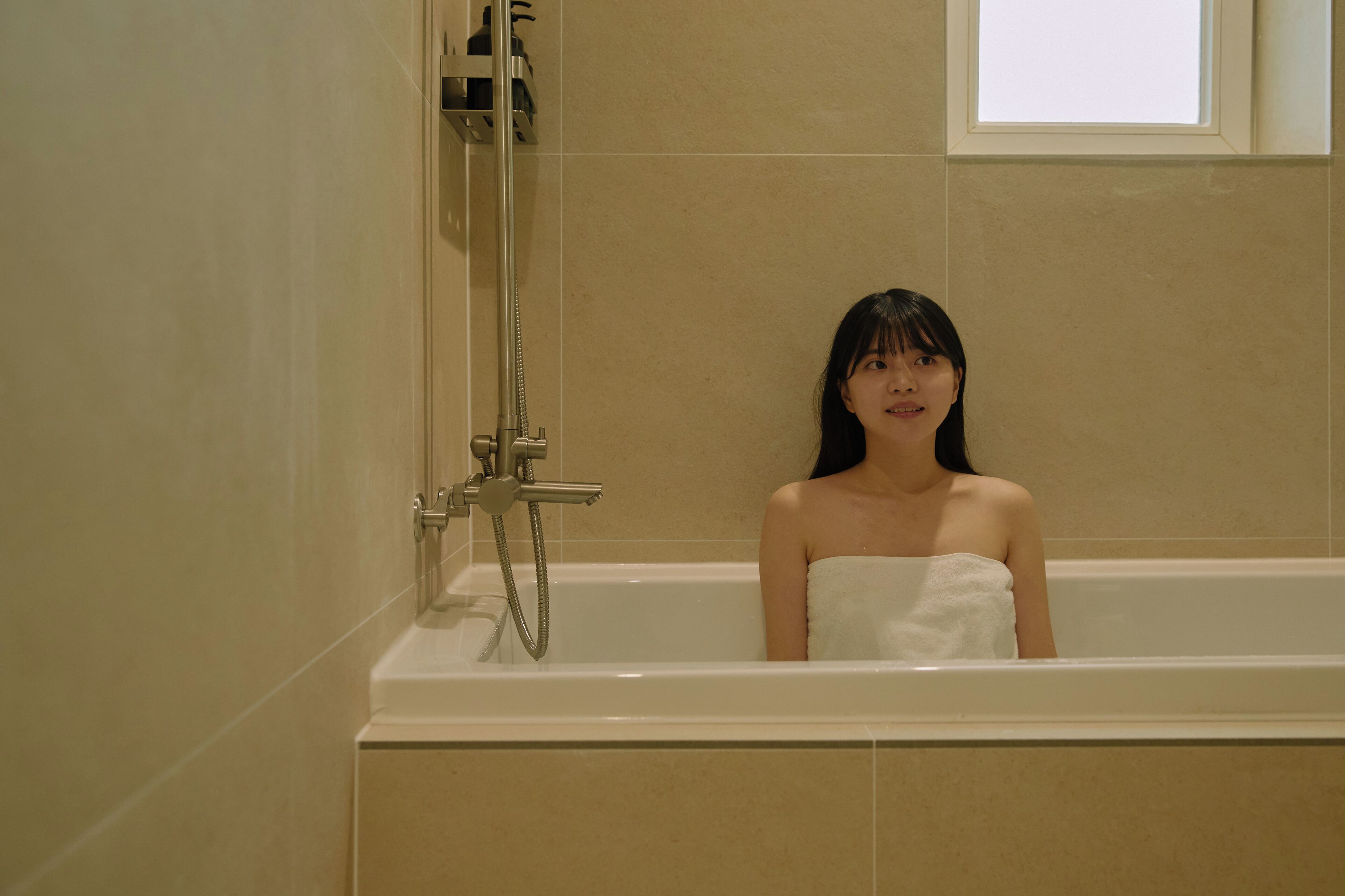 Una persona en una bañera con ducha y grifo.