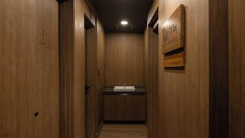 A narrow hallway with wooden walls and a sink in the center.