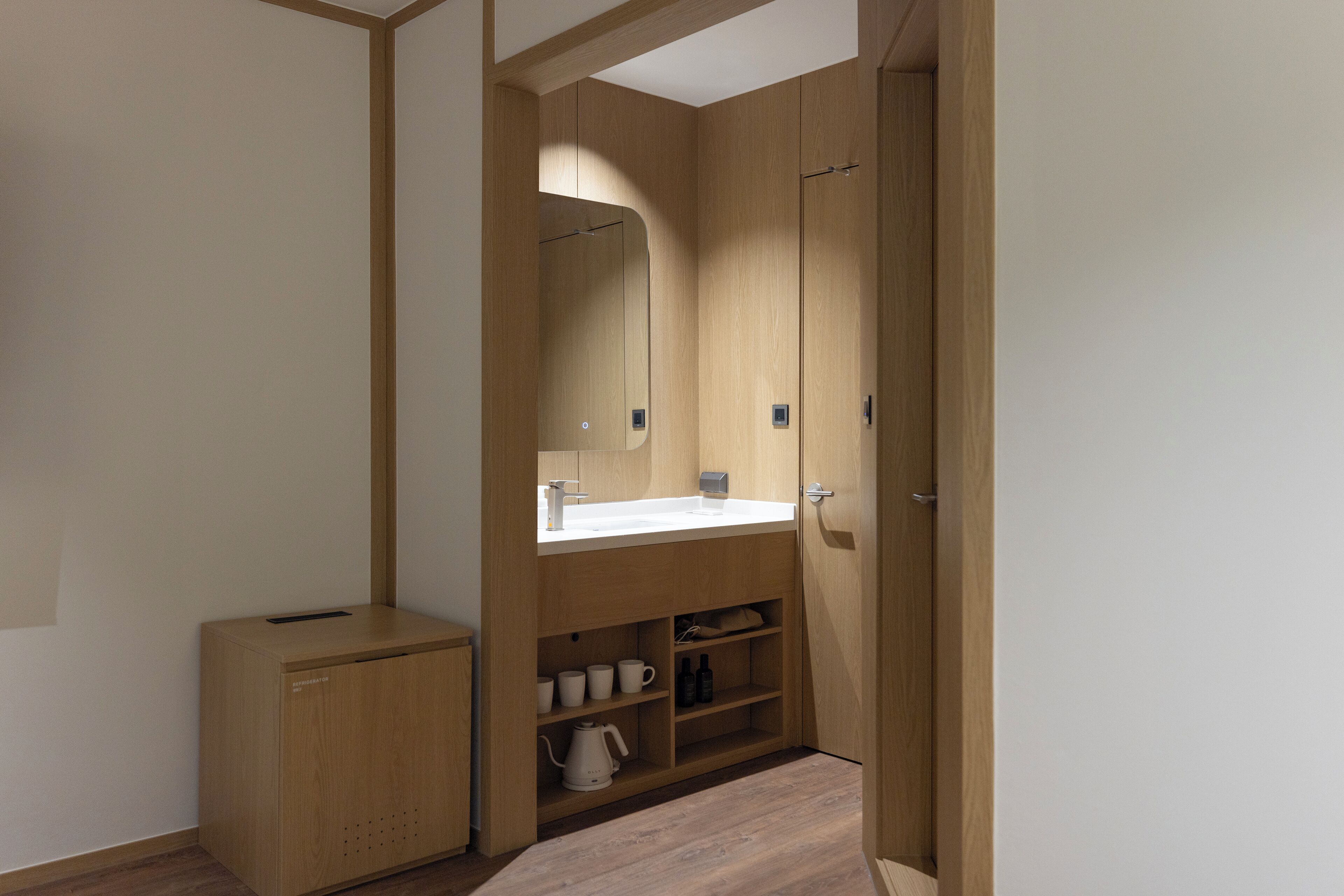 A modern bathroom with wooden cabinetry, a white sink, and a mirror above it.