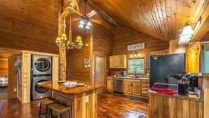 A spacious kitchen with wooden cabinets, a central island, and a built-in washer and dryer.