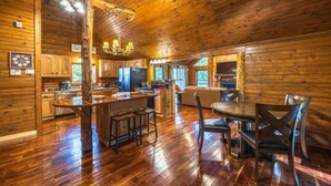 A spacious wooden cabin interior with a kitchen, dining area, and a large wooden ceiling.
