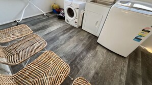 Un cuarto de lavandería con lavadora, secadora y tabla de planchar.