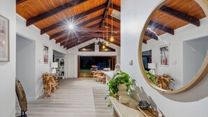 Een ruime kamer met een hoge plafond, houten balken, een grote spiegel en een houten vloer.