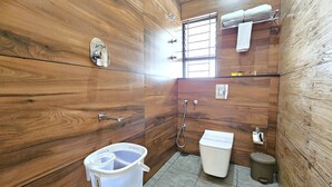 Um banheiro com paredes de madeira, vaso sanitário, pia, chuveiro e porta-toalhas.
