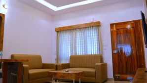 Uma sala de estar com sofá, mesa de centro, porta de madeira e ventilador de teto.