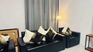 A modern living room with a black sofa set, decorative pillows, a wooden board game, and a floor lamp. - Peaceful Nadi Base Retreat (Nadi)