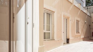 Un pasillo con paredes color beige y suelo de baldosas, que conduce a una puerta con ventana.