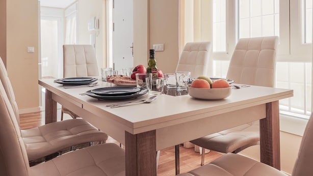 Comedor con una mesa dispuesta para cuatro personas, con platos, vasos y un frutero.
