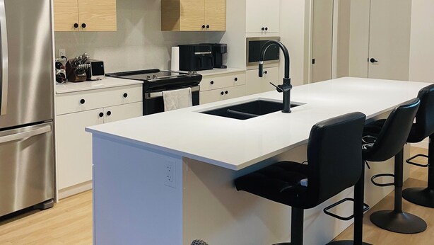 A modern kitchen with a central island, bar stools, and pendant lighting.