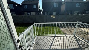A deck with a white railing, a brick wall, and a grassy yard.