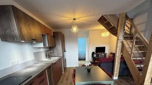 Eine moderne Küche mit Holzschränken, ein Essbereich mit Tisch und Stühlen sowie eine Treppe, die zu einer oberen Ebene führt.