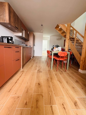 Eine moderne Küche mit Holzausstattung, ein Essbereich mit roten Stühlen und eine Holztreppe.