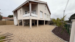 Uma casa de dois andares com varanda, entrada com pedrisco e uma pequena área de jardim.