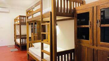 Ein Schlafraum mit Etagenbetten, Holzrahmen, einem roten Boden und einem Schrank mit Glastüren.