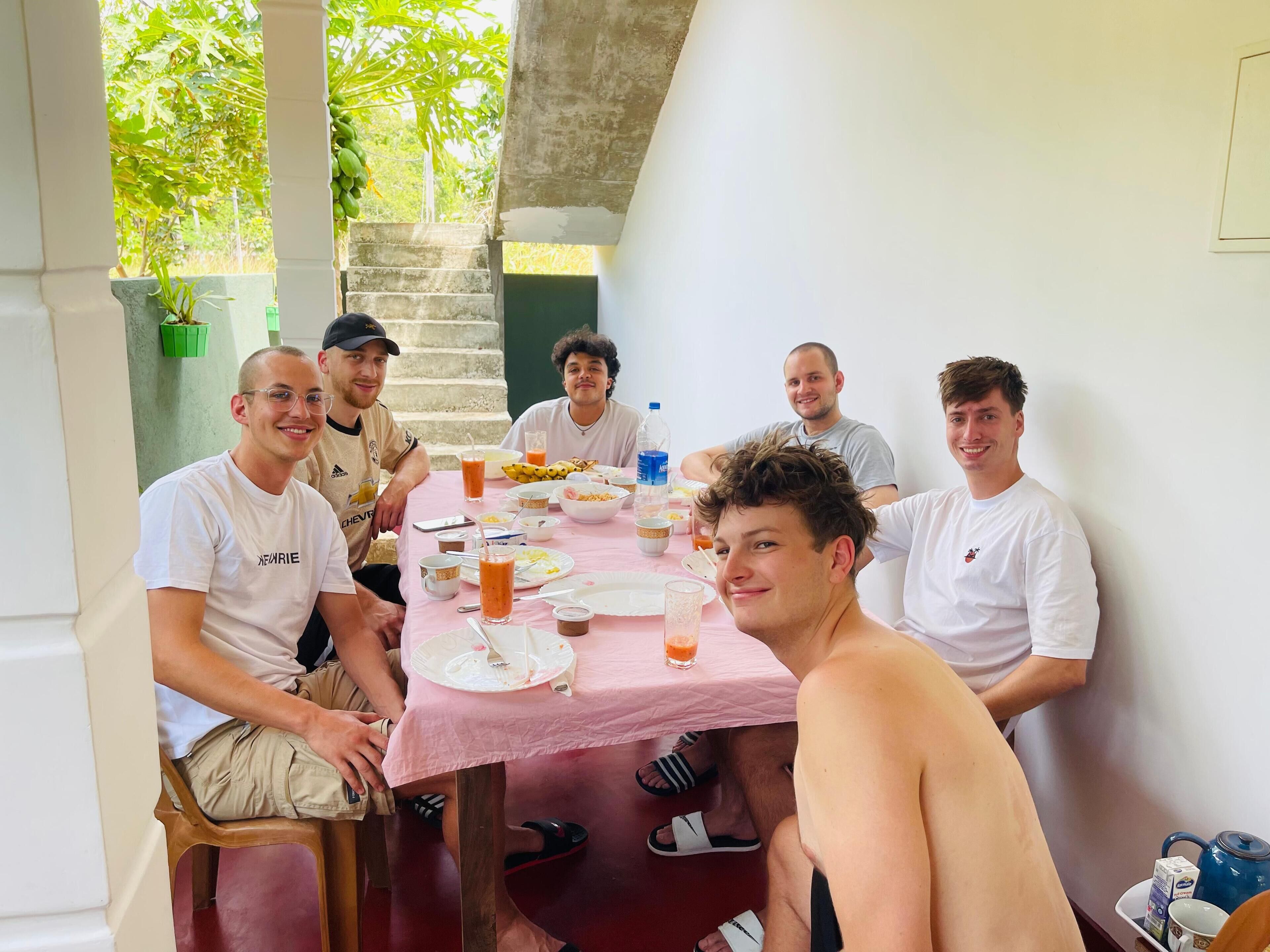 A group of people seated around a table with a pink tablecloth, enjoying a meal.