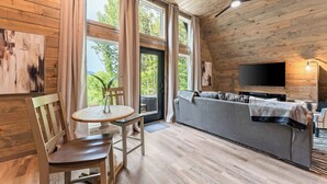 A cozy cabin interior with a wooden ceiling, a sofa, a TV, and a dining area with a table and chairs. - Romantic Sunsets Couples A Frame H/T Buffalo River (Parthenon)