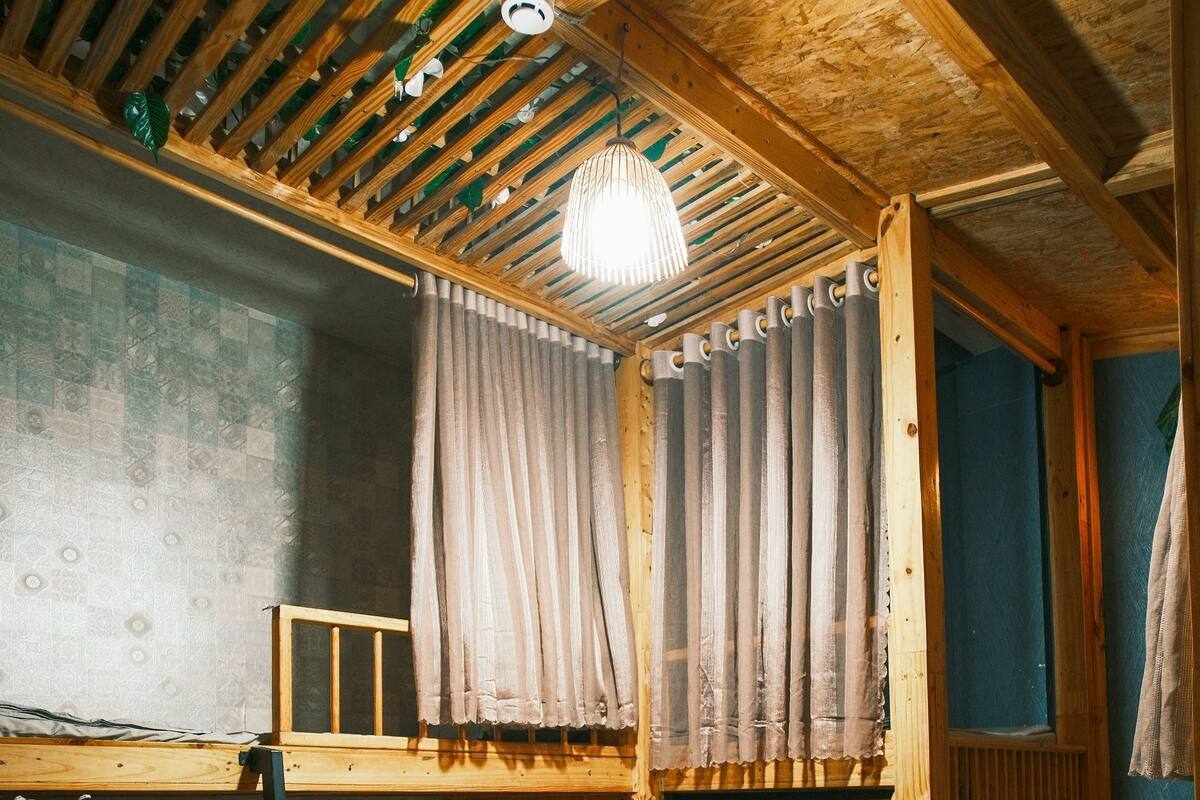 Una habitación de madera con literas, una escalera y una lámpara colgante.