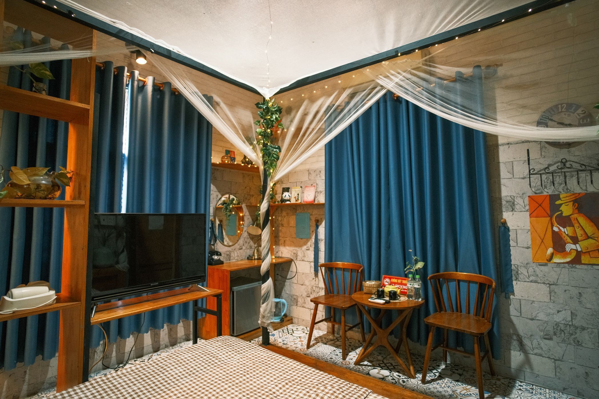 A cozy room with a flat-screen TV, wooden furniture, a small table with items, and blue curtains.