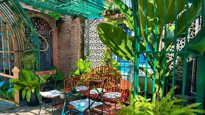 Un patio con un muro de ladrillo, una reja metálica y una mesa con sillas.
