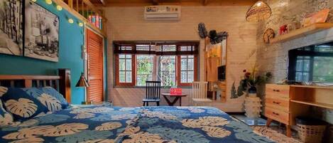 Un dormitorio con una cama grande, una silla, una mesita y un televisor.