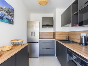 Une cuisine de taille réduite équipée d’un réfrigérateur, d’une cuisinière, d’un évier et d’un lave-vaisselle.