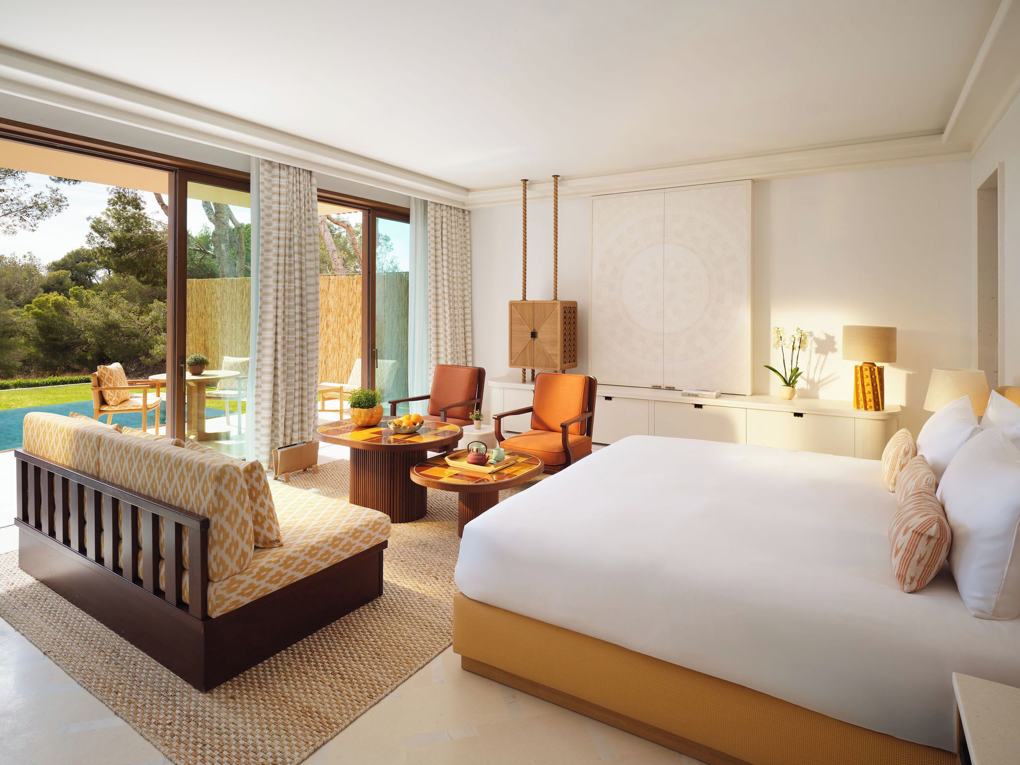 Une chambre d’hôtel avec un grand lit, un canapé, une table à manger et une vue sur la piscine.