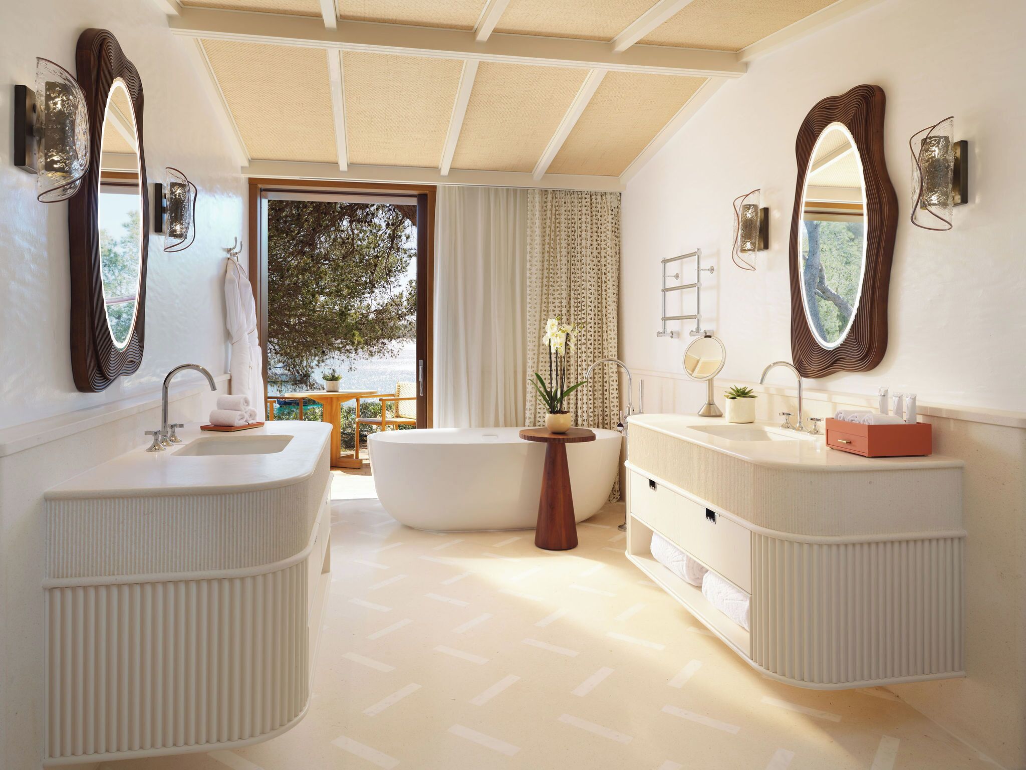 A modern bathroom with two sinks, a bathtub, and large mirrors.