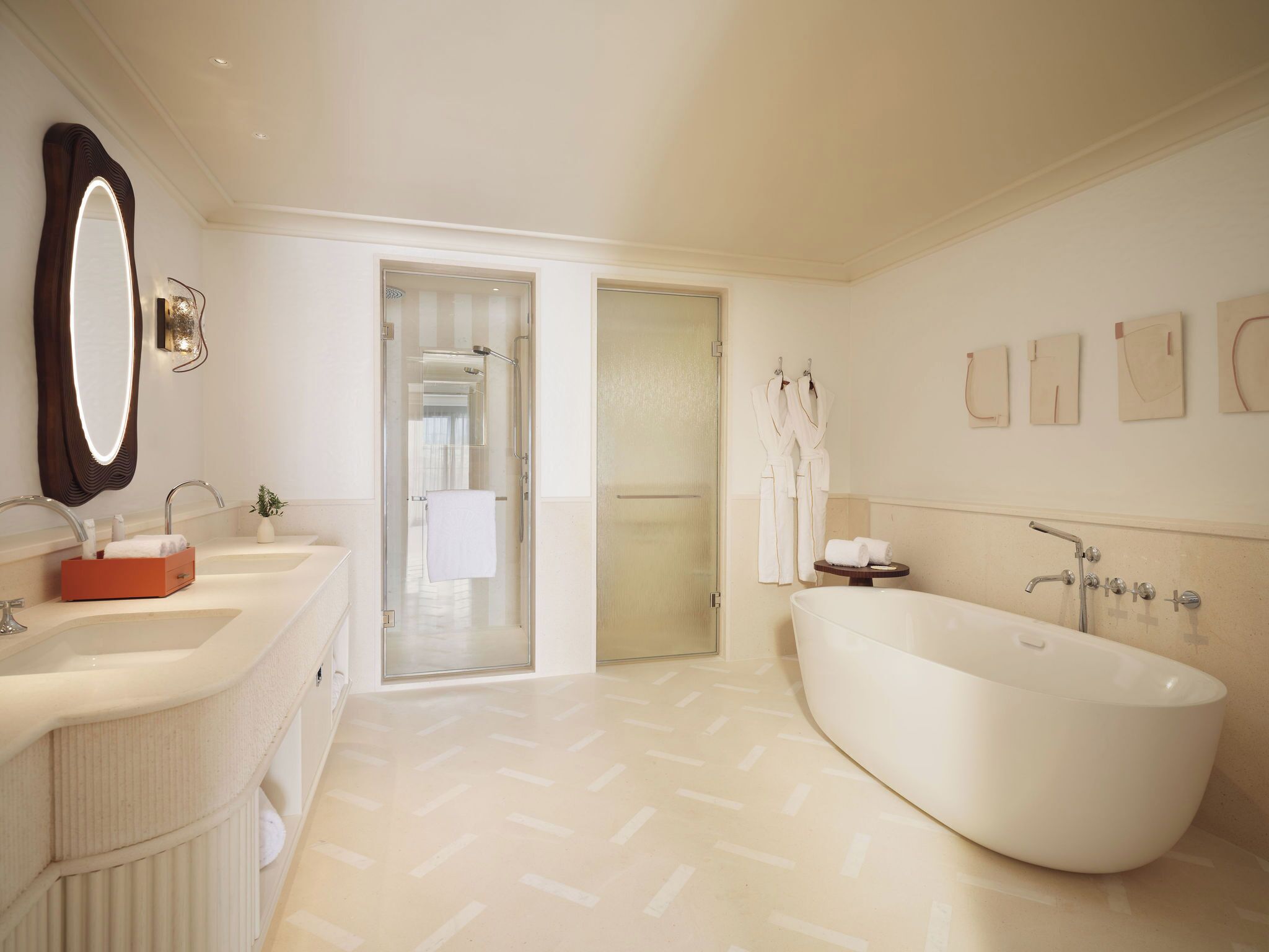 A modern bathroom with a freestanding bathtub, a large mirror, and a vanity with two sinks.
