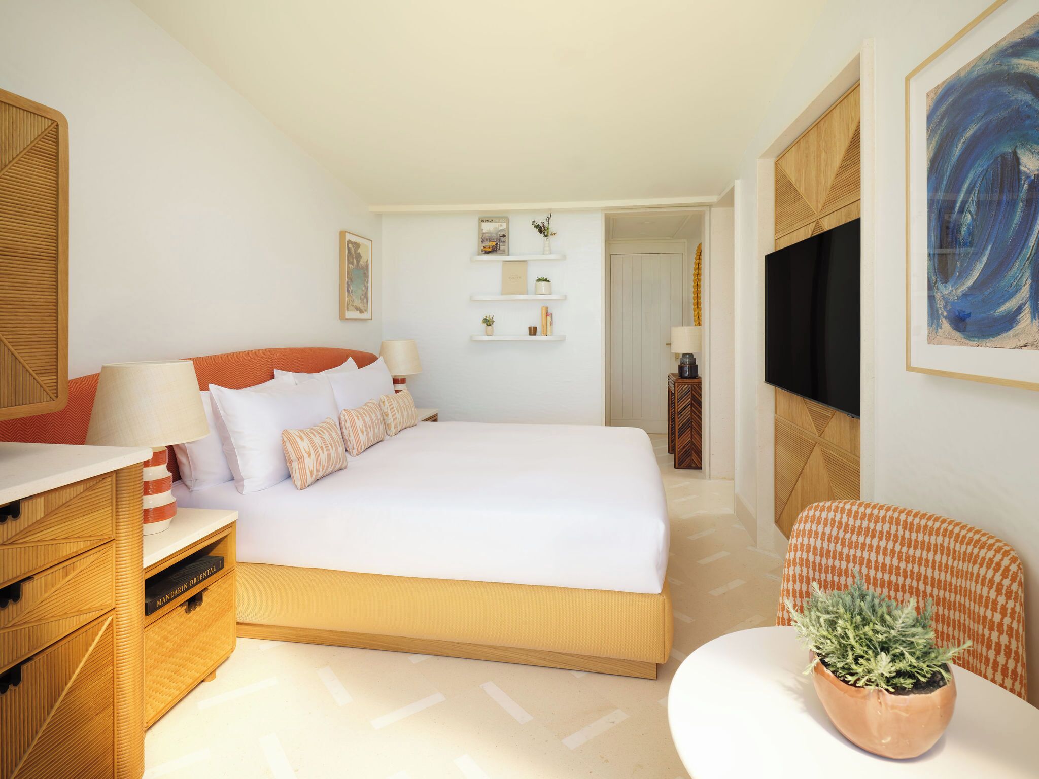 Une chambre d’hôtel bien rangée, avec un lit, des tables de chevet, une télévision et une petite plante.