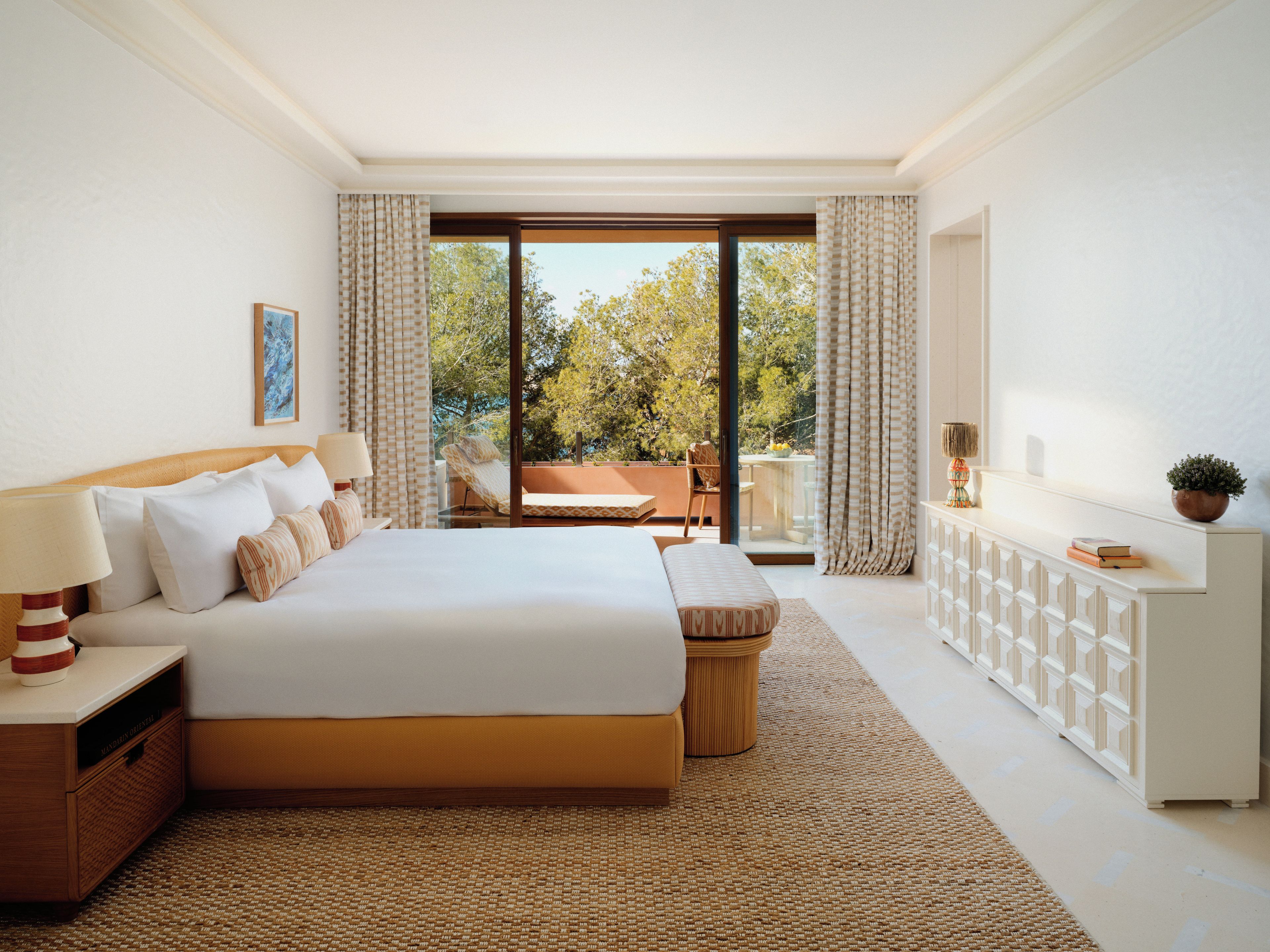 Une chambre d’hôtel avec un grand lit, un coin salon avec vue et une console blanche.